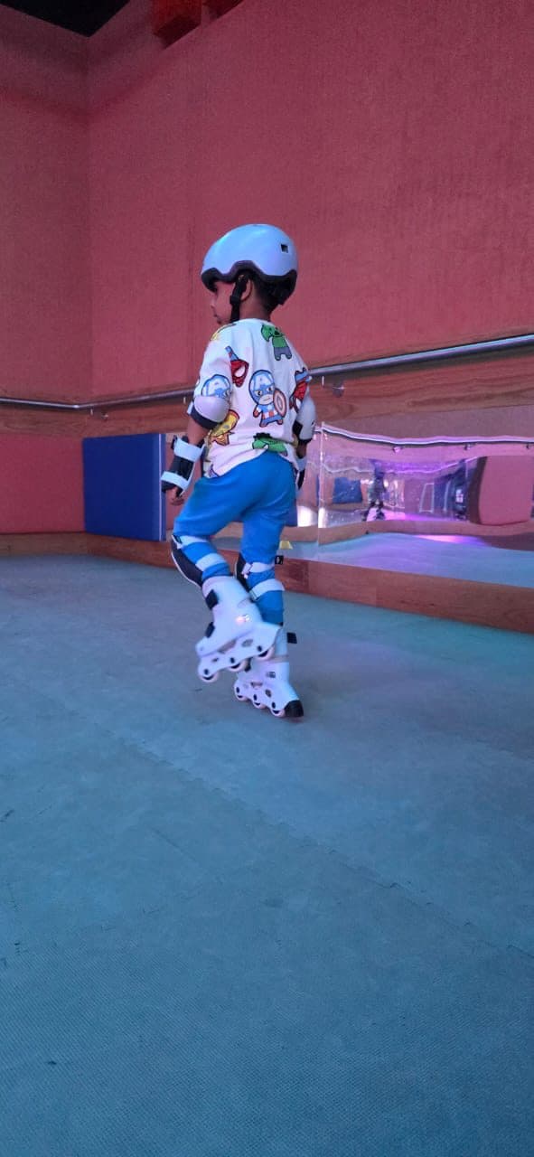 Young skater in protective gear rolling across an indoor rink